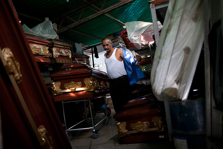 Caracas : Oswaldo Rivas smokes a cigarette while changing at a casket store 