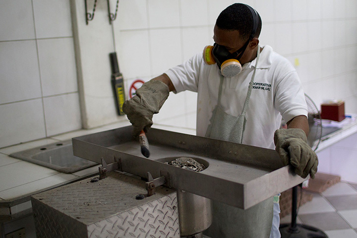 Caracas : A worker collects the remains of a deceased person following a cremation at