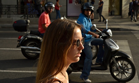 Two men look at a young woman on a street