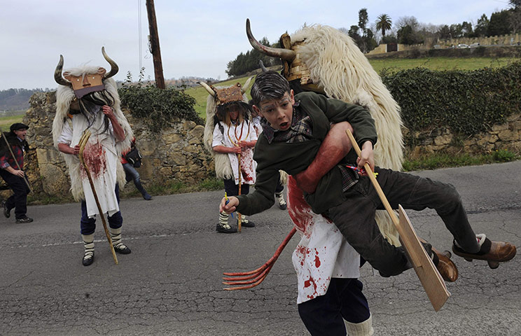 20 Photos: A member of a folk group takes hold of a child during a parade in Valdesoto, Spain