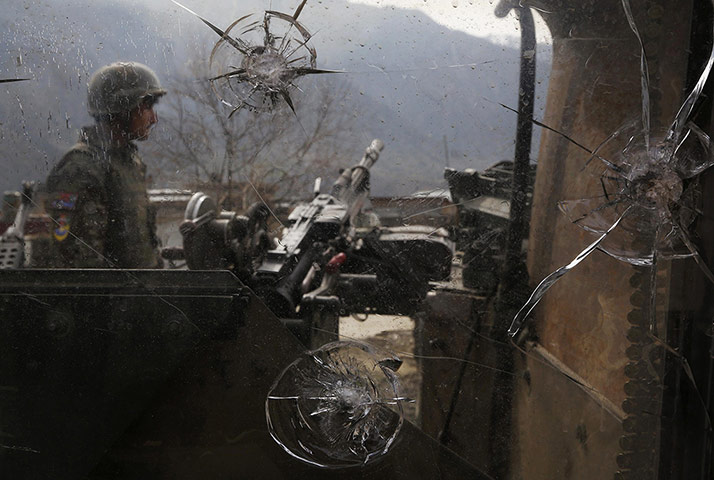 20 Photos: An Afghan National Army soldier is seen through damaged glass in Nari