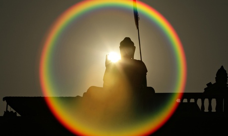 A Buddha statue is silhouetted on a hill on the outskirts of Phnom Penh, Cambodia