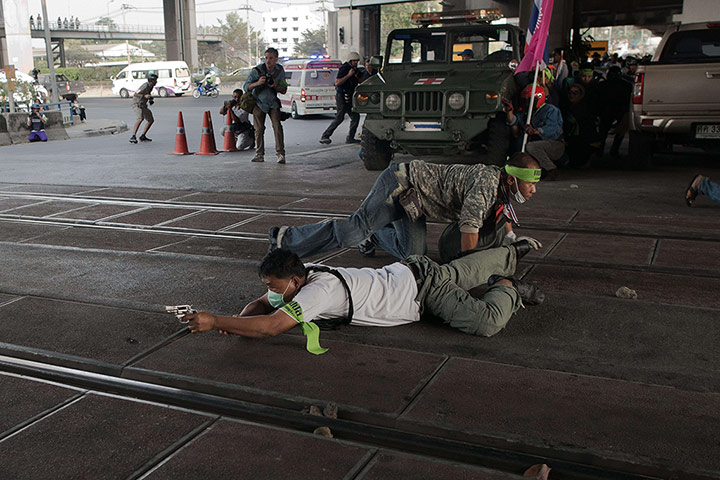 20 Photos: A Thai anti-government protester takes cover and aims his gun