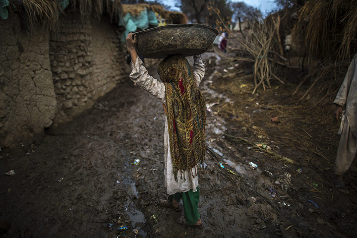 20 Photos: An Afghan girl walks toward her makeshift shelter in a slum near Islamabad
