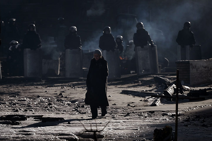 20 Photos: A woman walks in front of riot police at a road block in Kiev