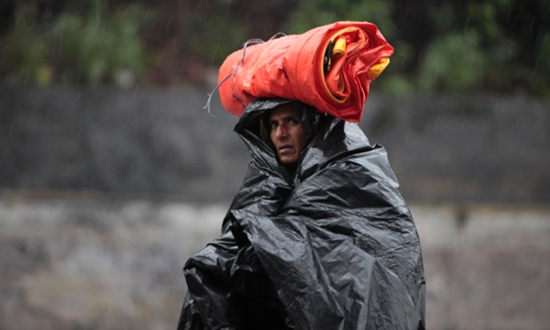 A man protects himself with a plastic sheet in the rain in Jammu, India,.