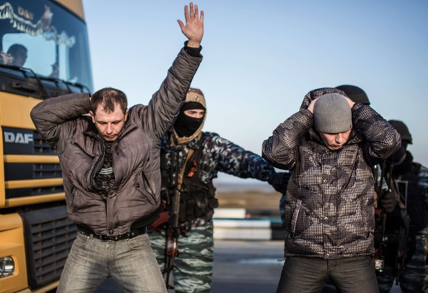 Men hold their hands up on their heads as they are searched by pro-Russian servicemen at Chongar checkpoint blocking the entrance to Crimea.