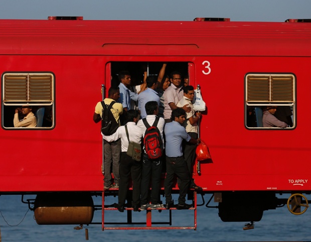 People hang onto a crowded local passenger train as they travel to Colombo, Sri Lanka.