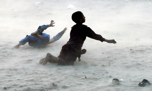 Pakistani children fall during a dust storm on the outskirts of Lahore as heavy rain and stormy weather has hit parts of northern Pakistan.