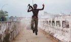 Joseph Duo, a Liberian militia commander loyal to the government, exults after firing a rocket-propelled grenade at rebel forces in Monrovia, Liberia.