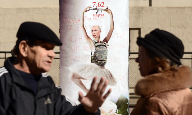 People speak in front of a placard depicting the Russian president, Vladimir Putin, as a dancing ballerina wearing a bulletproof vest with Kalashnikov machine gun.