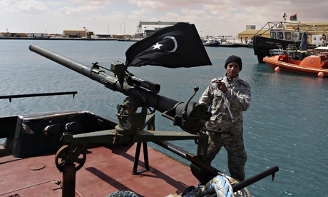 A rebel under Ibrahim Jathran holds the Cyrenaica flag while standing on a boat at Es Sider port.