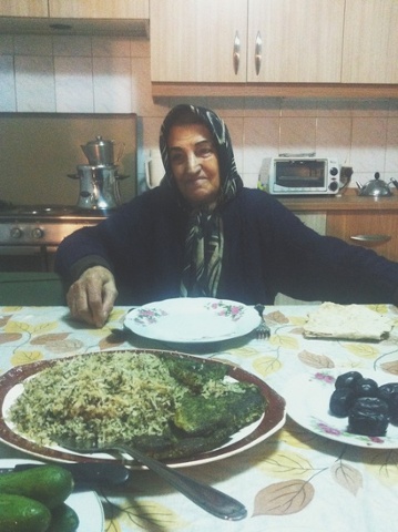 an iranian woman sitting at a kitchen table in front of a plate of koo koo sabzi