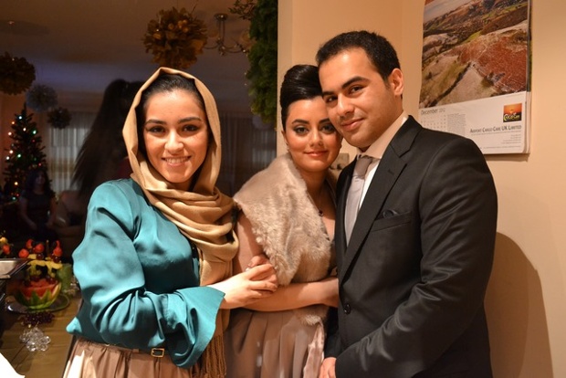 a woman wearing a headscarf next to an engaged couple with christmas decorations in the background