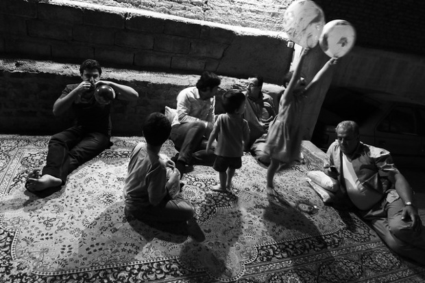 a family sitting on a carpet with one child playing with balloons