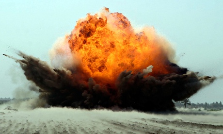 An explosion erupts from the detonation of a weapons cache.