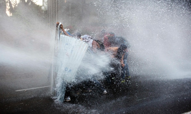Caracas, Venezuela: Anti-government demonstrators take cover from a police water cannon.