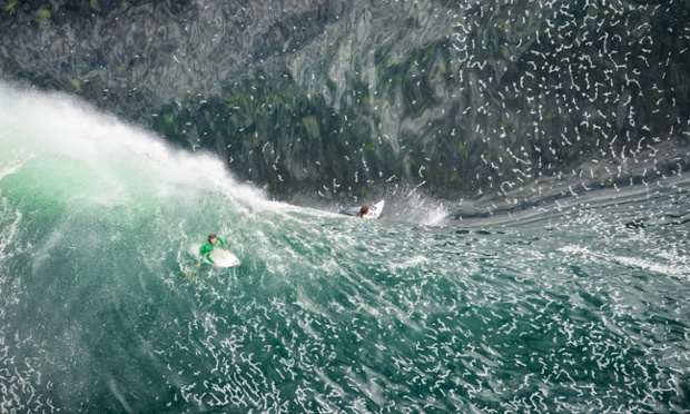 Aerial photography of big wave surfing on Ours surf break, Sydney, Australia. Situated at Cape Solander in Botany Bay, the wave breaks ten metres from the rocks and on water only a few feet deep. When the waves reach this height the only possible way to catch the waves is by being towed in behind a jet ski.