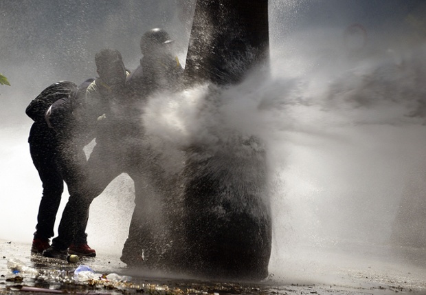 Journalists take shelter behind a tree during clashes between the National Police and anti-government activists as protests continue against Venezuelan President Nicolas Maduro, in Caracas. 