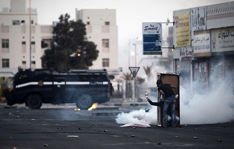 20 Photos: Bahraini protesters behind a shield during clashes with riot police