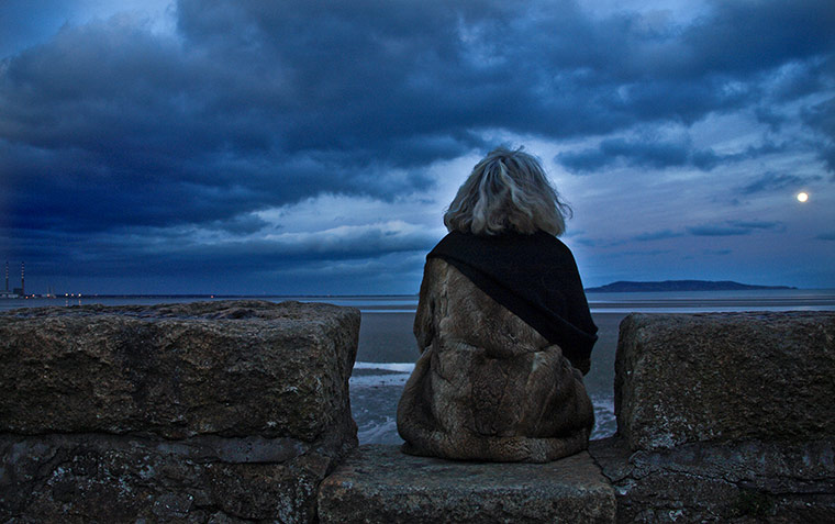 In Pictures - Lost: woman sitting on stony wall facing moon