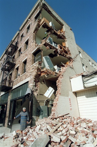 A woman walks over rubble after the Northridge earthquake, January 1994