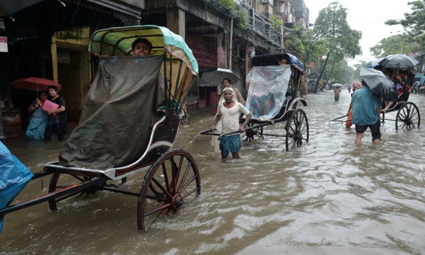 Rickshaw pullers carry passengers through water-logged streets in Kolkata 