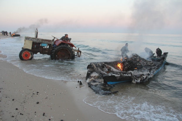 A destroyed fishing boat is hauled up onto the shore, close to Rafah.