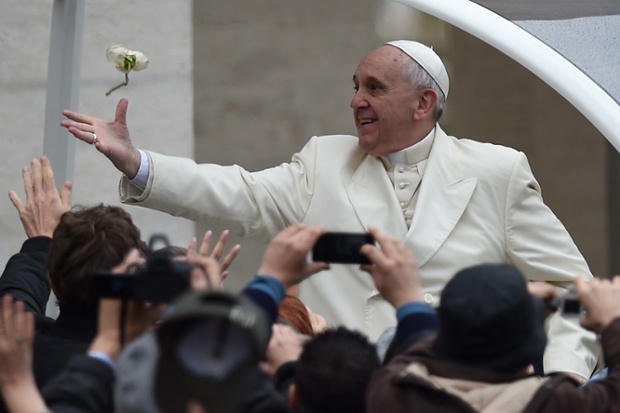 Pope Francis tries to catch a white rose thrown by a pilgrim as he arrives for his general audience at St Peter's square at the Vatican.