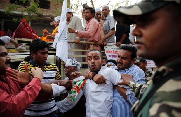 An man who was waving a black flag is restrained during an election rally for the Aam Aadmi Party in Varanasi, India. People threw ink and eggs during the rally.