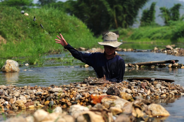 A worker removes stones as he pans for gold in Lampang, Thailand.