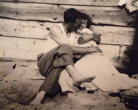 Man kissing woman on beach in 1950s
