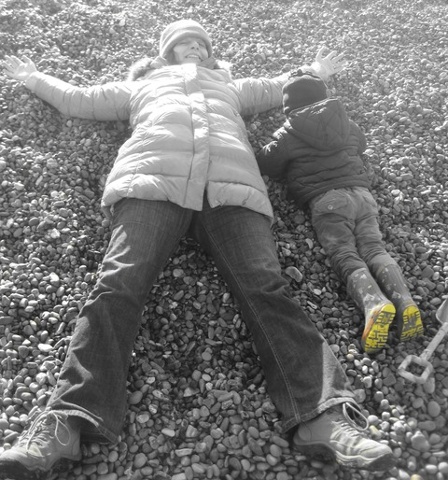 Grandmother making star shape on beach with grand son 