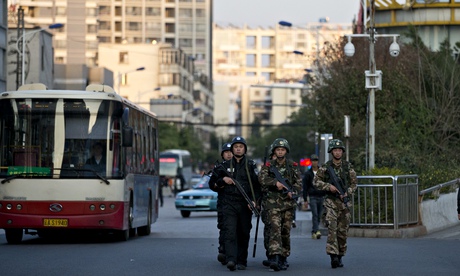 Armed policemen and paramilitary policemen patrol a street near Kunming railway station