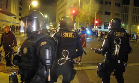 Riot police stand guard in front of protesters in downtown Albuquerque Sunday night.