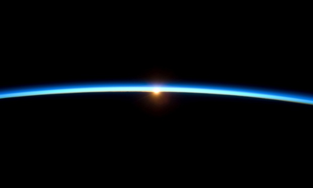 The thin line of Earth's atmosphere and the setting sun are featured in this photo by a crew member on the International Space Station while the space shuttle Atlantis remains docked with the station