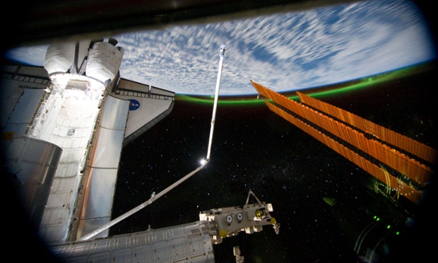Photographed from the International Space Station, this panoramic view looks past the docked space shuttle Atlantis's cargo bay and part of the station, including a solar array panel, towards Earth, as the joint complex passes over the southern hemisphere. Aurora Australis, or the Southern Lights, and a number of stars can be seen on Earth's horizon