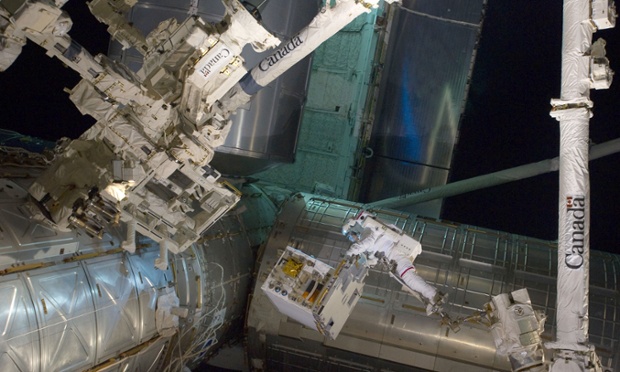 With his feet secured on a restraint on the space station remote manipulator system's robotic arm, or Canadarm2, Mike Fossum (centre) holds the robotics refuelling mission payload, which was the focus of one of the primary chores accomplished on a six and a half hour spacewalk