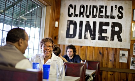 Customers in the Home Grown restaurant sit in front of a sign left behind from the filming of 