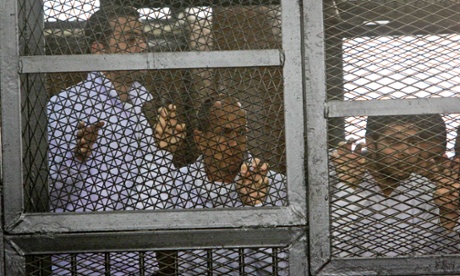 Al-Jazeera producer Baher Mohamed, left, and correspondent Peter Greste, centre, in the defendants' cage in a Cairo courtroom