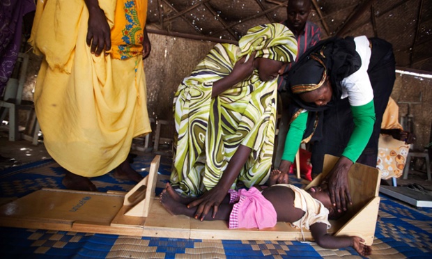 Volunteers measuring a 2-year-old child suffering from malnutrition in a food distribution centre in a camp for internally displaced people (IDP) in Tawila, North Darfur.