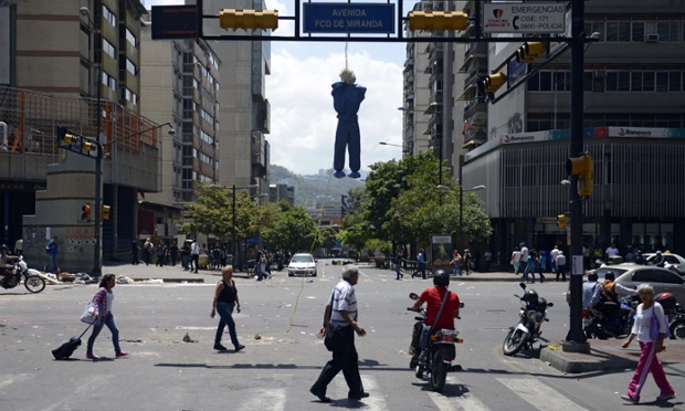 People walk underneath a hanging effigy depicting a Cuban doctor in a protest against Venezuelan President Nicolas Maduro government in Caracas.