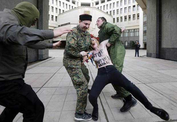 Pro-Russian activists detain a member of the feminist group FEMEN protesting against Putin's policy concerning Ukraine near the Crimean parliament in Simferopol, Ukraine.
