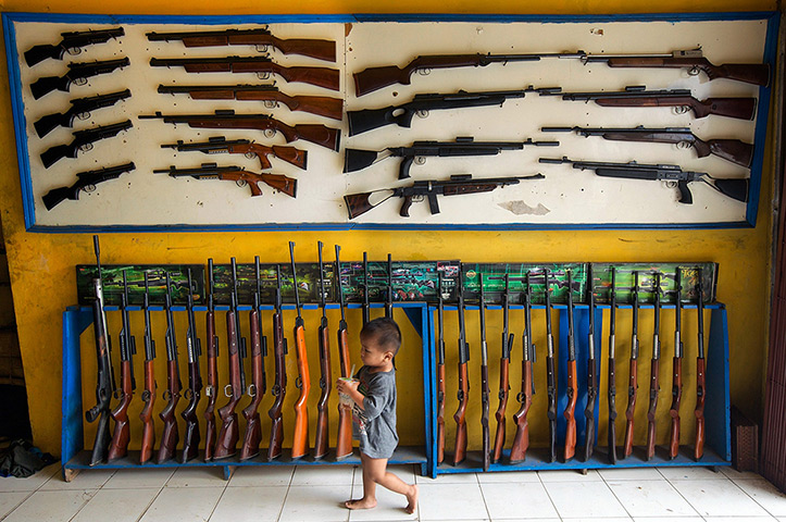 Air rifle capital: The shop owner's small son walks past air rifles on display at the shop nea