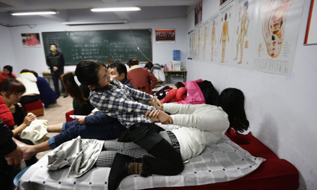 Push me-pull you: A student stretches the back of a fellow student during a massage training course at Huaxia Liangtse, China.