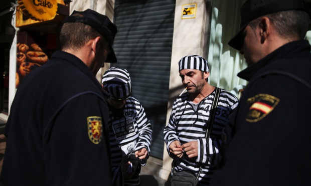 Police officers take the ID of protesters dressed as prisoners during a demonstration against mortgage fraud in Madrid, Spain.