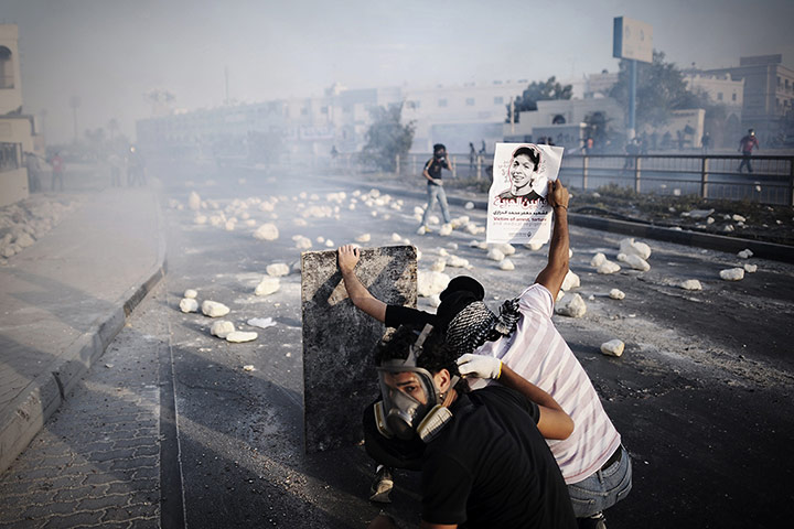 20 Photos: Bahraini protesters take cover behind a shield during clashes with police