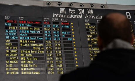 People stand beside the arrival board in Beijing showing the missing Malaysia Airlines flight