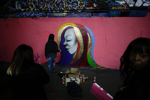 An artist called Hazard paints during a graffiti art event in support of Breast Cancer Care as part of International Women's Day celebrations in London