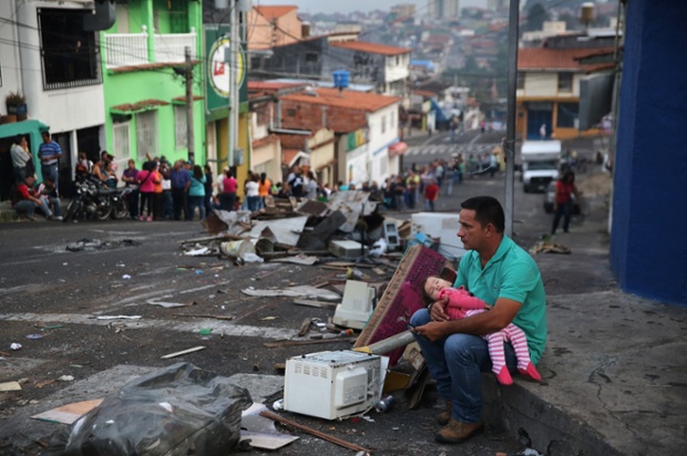A father and daughter rest while someone holds their place in a long queue to buy basic foodstuffs at a supermarket in San Cristobal, Venezuela. Shortage of such products as flour, milk and sugar have made life increasingly difficult for residents of Tachira, which has been a focal point for anti-government protests for almost a month.
